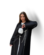 Model wearing a premium black abaya with white rose detailing and contrast piping – Muhajeerah